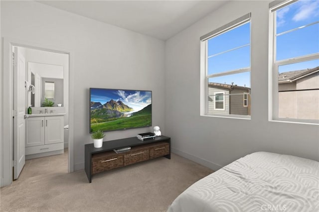 bedroom featuring light colored carpet, a sink, ensuite bath, and baseboards