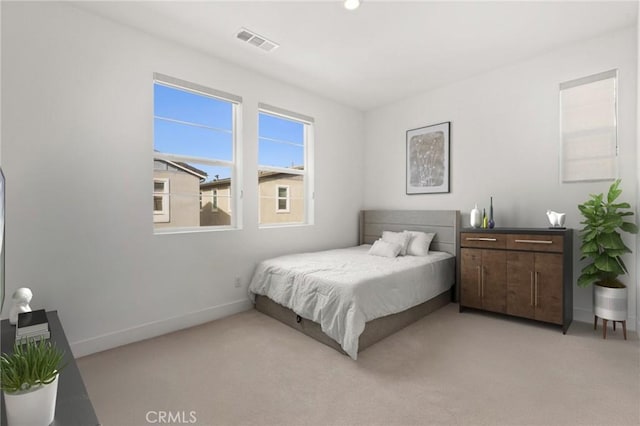 bedroom with baseboards, visible vents, and light colored carpet