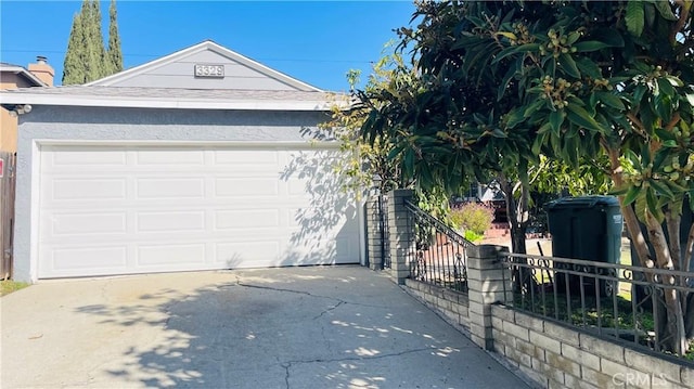 garage featuring concrete driveway and fence