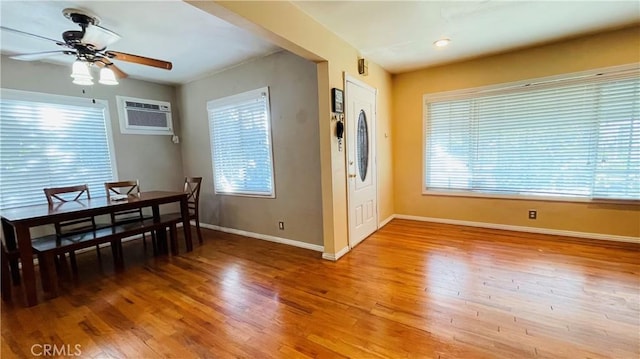 dining space featuring light wood finished floors, ceiling fan, baseboards, and a wall mounted AC