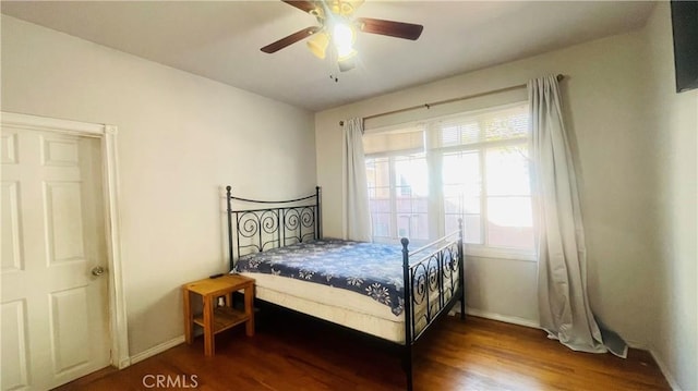 bedroom featuring a ceiling fan, baseboards, and wood finished floors