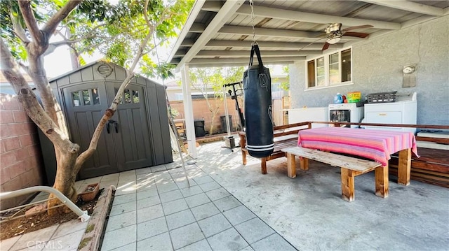 view of patio / terrace with an outbuilding, washing machine and clothes dryer, a storage unit, a ceiling fan, and fence