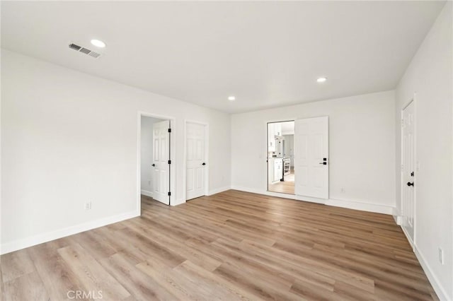 empty room featuring light wood finished floors, recessed lighting, visible vents, and baseboards