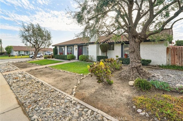 single story home with fence, a tiled roof, a front lawn, and stucco siding