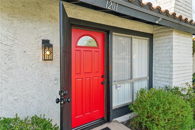 view of exterior entry with a tiled roof and stucco siding