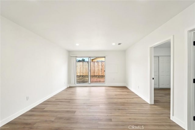 empty room with baseboards, recessed lighting, and light wood-style floors