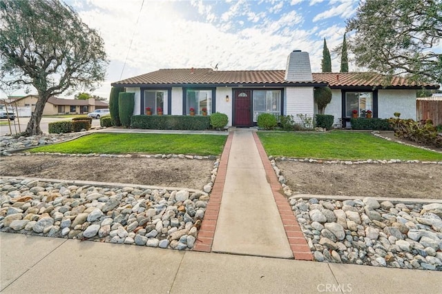 view of front facade with a front lawn, a chimney, a tile roof, and stucco siding