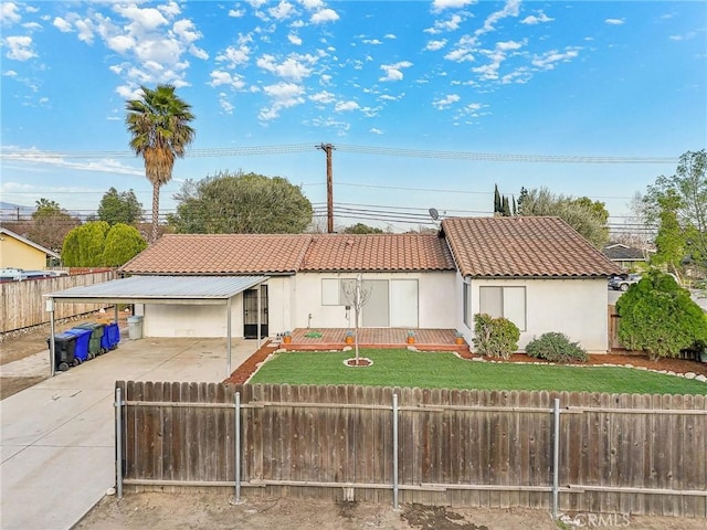 view of front of property with driveway, stucco siding, a fenced front yard, a tiled roof, and a front yard