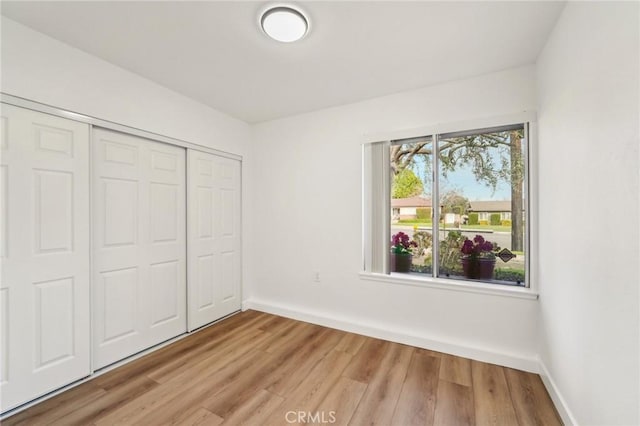 unfurnished bedroom featuring baseboards, a closet, and light wood-style floors