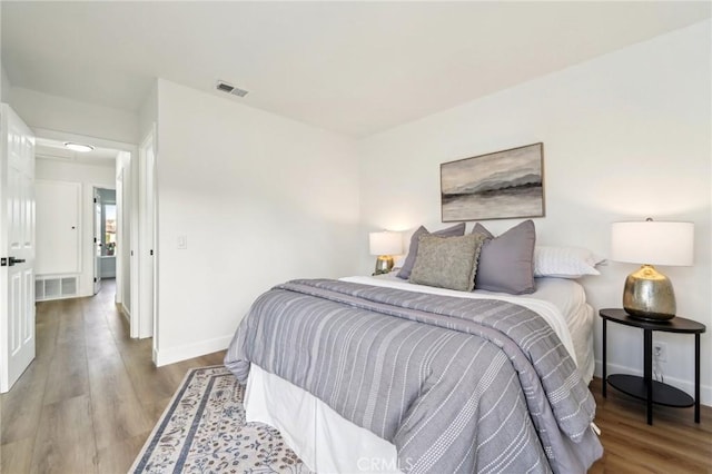 bedroom featuring baseboards, visible vents, and wood finished floors