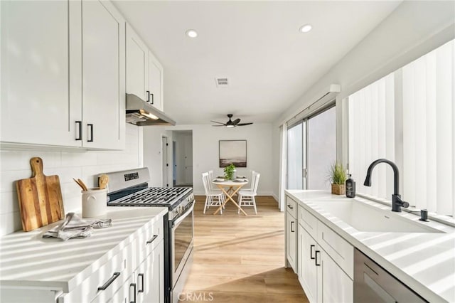 kitchen with light countertops, visible vents, appliances with stainless steel finishes, a sink, and under cabinet range hood