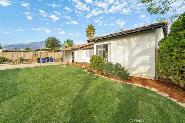 rear view of house with stucco siding, fence, a patio, and a yard