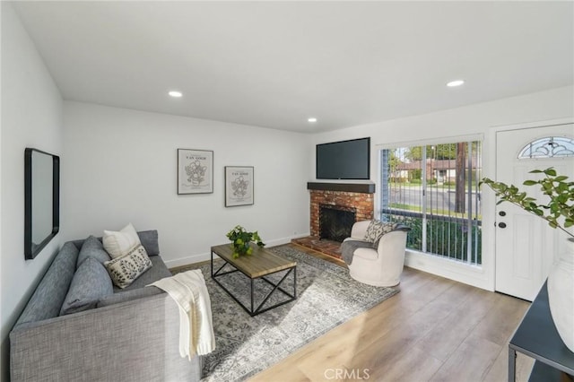 living area with a fireplace, baseboards, wood finished floors, and recessed lighting