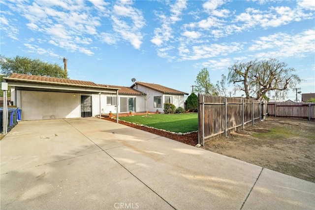 view of front of home featuring fence private yard, driveway, stucco siding, a carport, and a front lawn