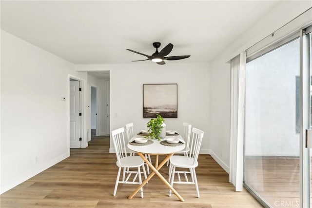 dining room with ceiling fan, light wood-style flooring, and baseboards