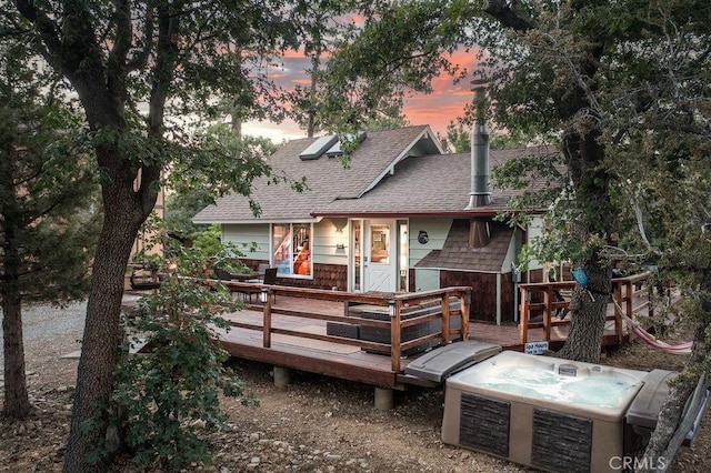 back of house featuring a hot tub, a deck, and a shingled roof