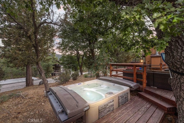 deck at dusk featuring a hot tub