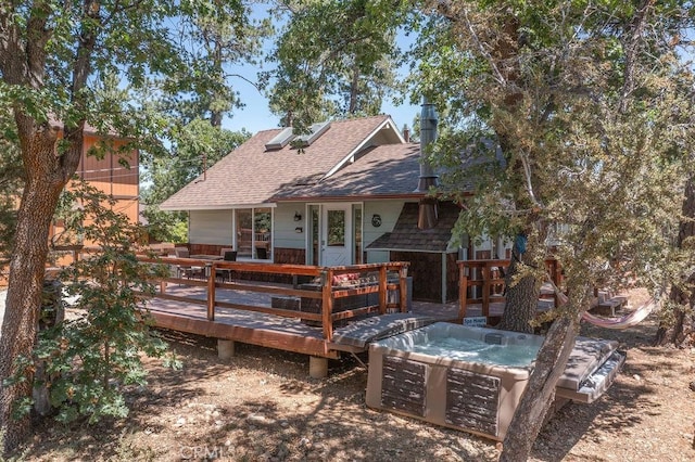 back of property with a deck, a shingled roof, and a hot tub