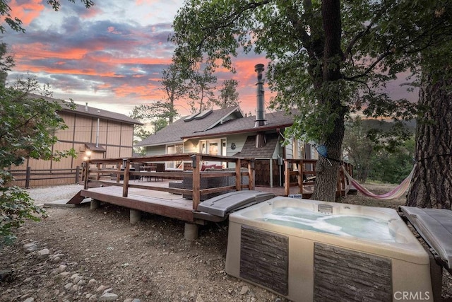 deck at dusk with fence and a hot tub