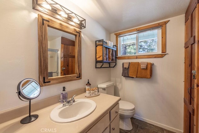 full bathroom featuring a shower with shower door, vanity, toilet, and baseboards