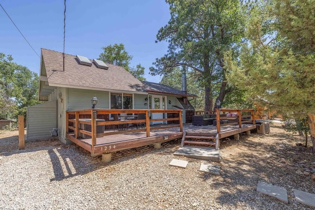 back of property featuring a deck and roof with shingles