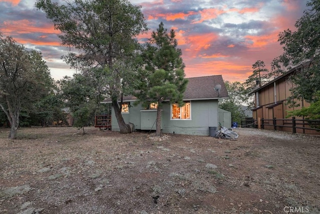 back of house featuring roof with shingles and fence