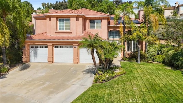 mediterranean / spanish home featuring an attached garage, a tile roof, concrete driveway, stucco siding, and a front lawn