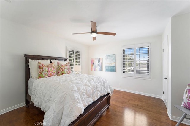 bedroom featuring multiple windows, a ceiling fan, baseboards, and wood finished floors