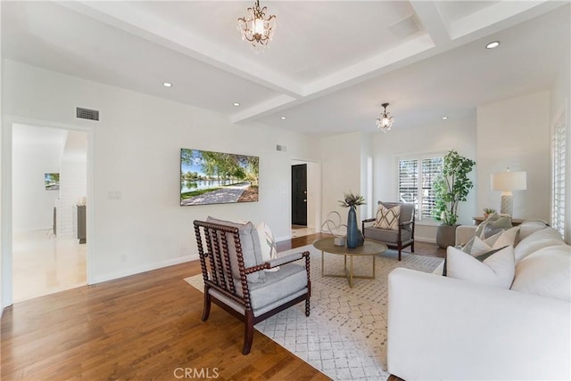 living area featuring light wood-type flooring, visible vents, a notable chandelier, and beamed ceiling