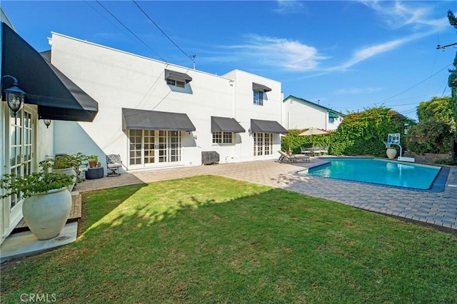 outdoor pool with a patio area, a lawn, and french doors