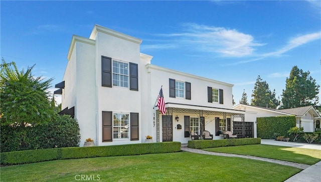 view of front facade with stucco siding, driveway, a front lawn, and a garage