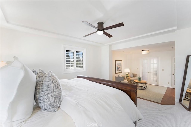 bedroom featuring french doors, a raised ceiling, ceiling fan, and carpet flooring