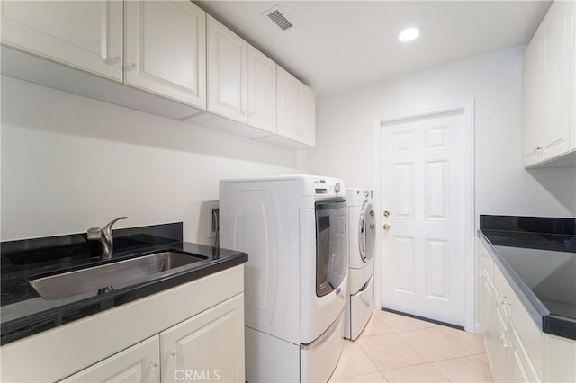 clothes washing area featuring washing machine and clothes dryer, visible vents, light tile patterned flooring, cabinet space, and a sink