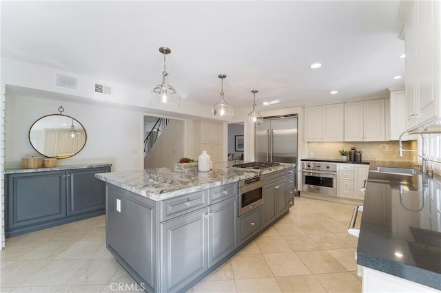 kitchen featuring visible vents, a sink, backsplash, a center island, and appliances with stainless steel finishes