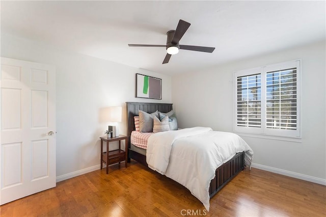 bedroom with ceiling fan, baseboards, and wood finished floors