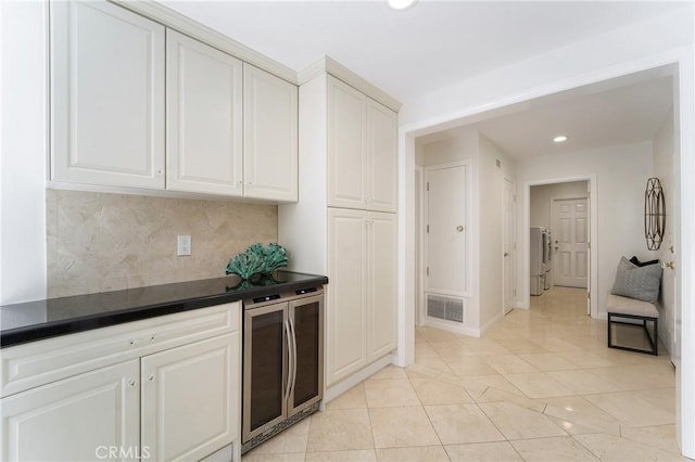 kitchen featuring dark countertops, visible vents, tasteful backsplash, wine cooler, and washer / clothes dryer