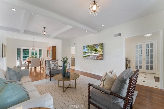 living room with beamed ceiling, visible vents, wood finished floors, french doors, and an inviting chandelier