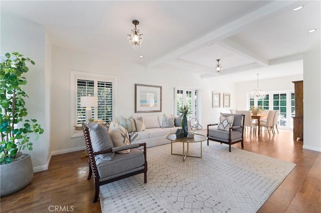 living room featuring beam ceiling, baseboards, an inviting chandelier, and wood finished floors