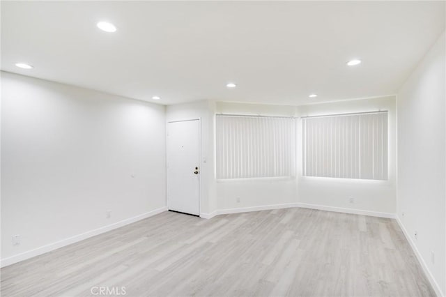 basement featuring baseboards, light wood finished floors, and recessed lighting