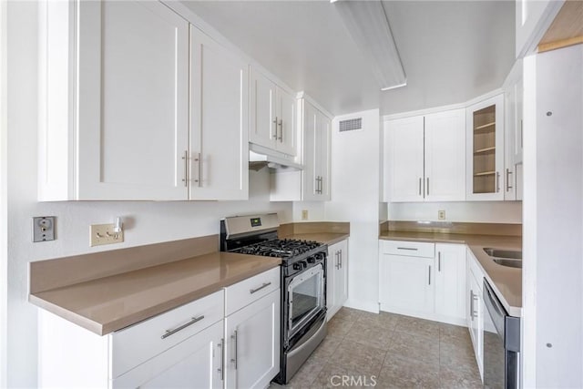 kitchen featuring visible vents, white cabinets, glass insert cabinets, appliances with stainless steel finishes, and under cabinet range hood