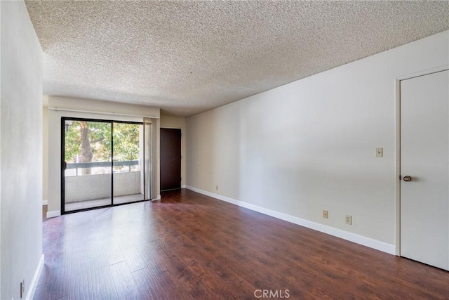 spare room with a textured ceiling, wood finished floors, and baseboards