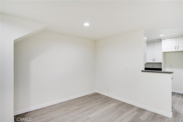 kitchen featuring baseboards, dark countertops, light wood-style floors, white cabinetry, and recessed lighting