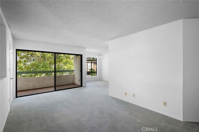 spare room featuring a chandelier, carpet, and a textured ceiling