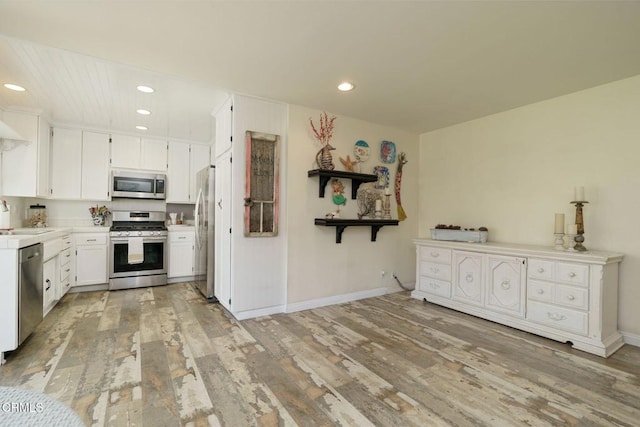 kitchen with white cabinets, appliances with stainless steel finishes, light wood-type flooring, a sink, and recessed lighting