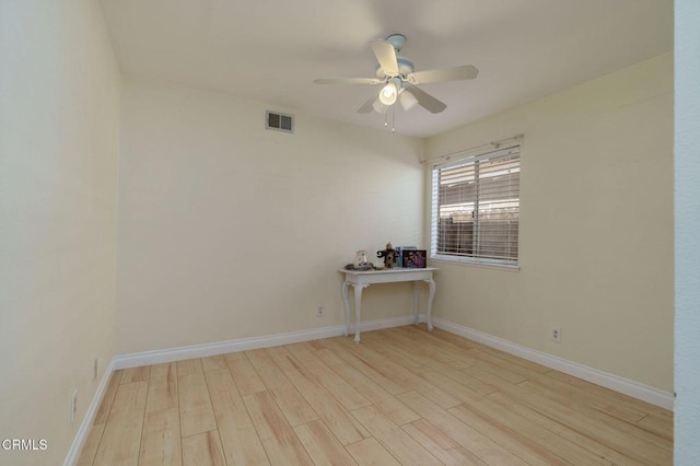 unfurnished room with a ceiling fan, wood finished floors, visible vents, and baseboards