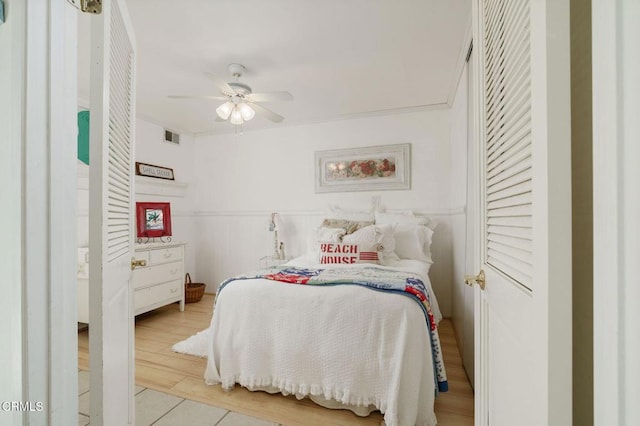 bedroom with ceiling fan, visible vents, crown molding, and wood finished floors