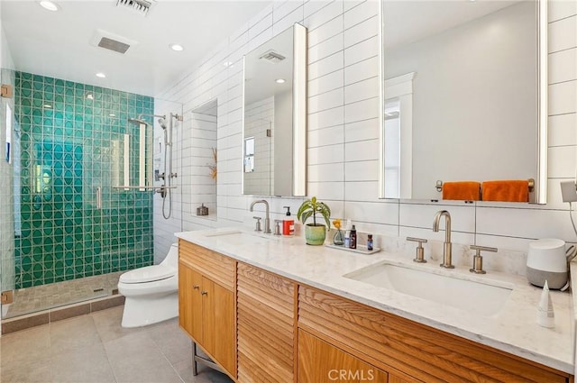 bathroom with toilet, a shower stall, tile walls, and a sink