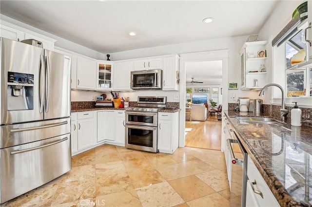 kitchen with white cabinets, dark stone counters, appliances with stainless steel finishes, open shelves, and a sink