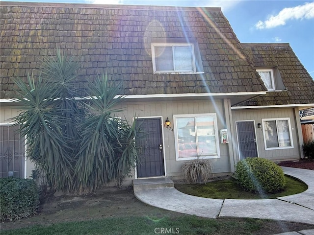 view of property featuring mansard roof and fence