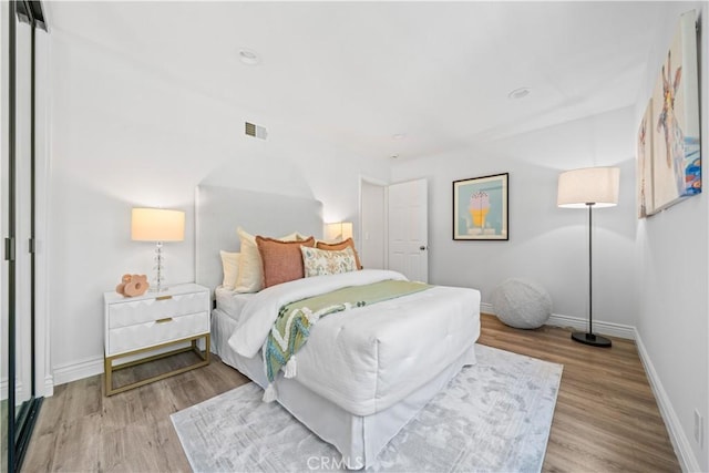 bedroom featuring visible vents, baseboards, and wood finished floors